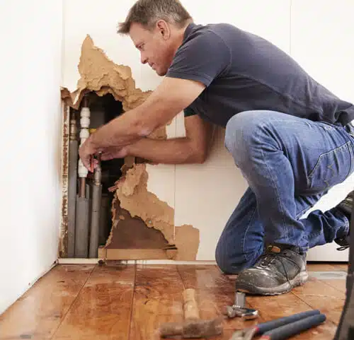 A professional from Black Diamond Restoration is fixing a hole in the wall, demonstrating quality craftsmanship.