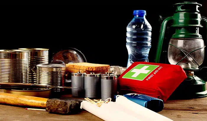 A collection of items including a can, lantern, flashlight, and multiple can openers, placed on a wooden surface.