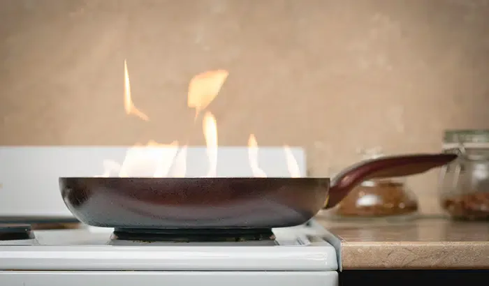 A pan with flames on a stove, fueled by wood.